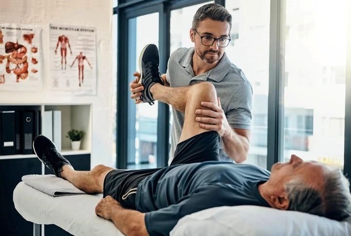 physical therapy on patients knee while they lay down on back